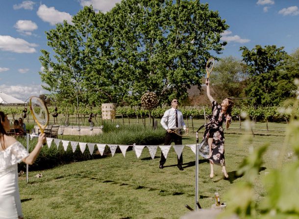 Wedding guests having fun playing badminton on lawn